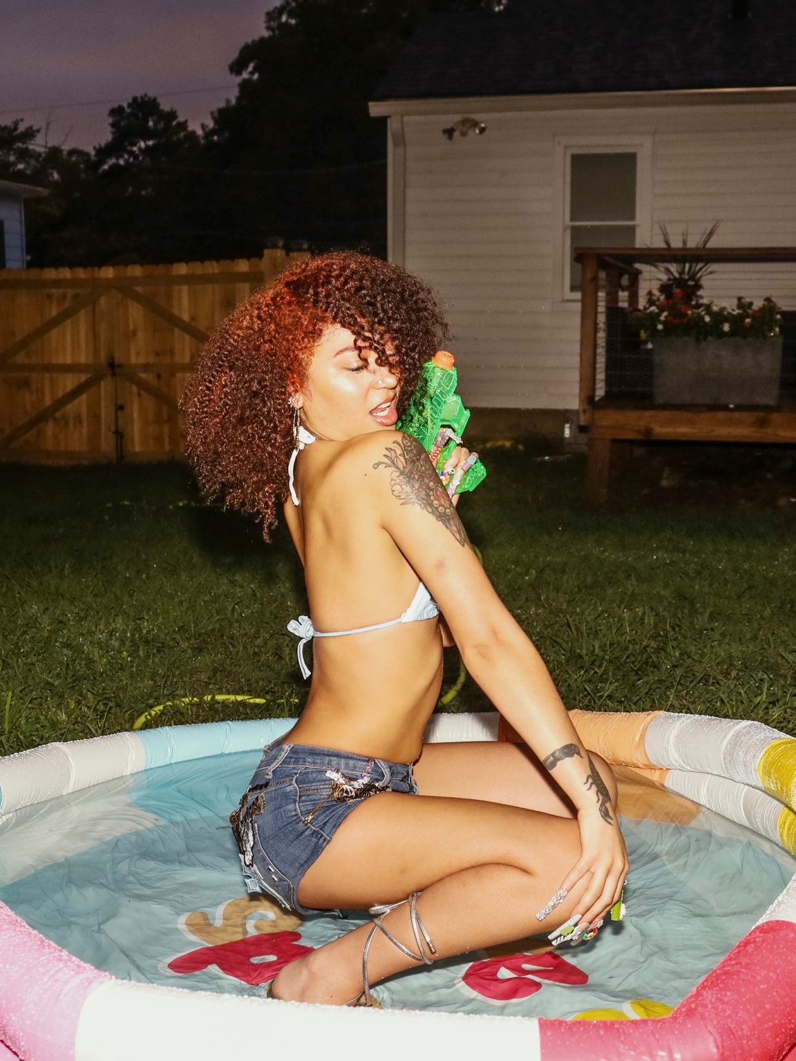 Lailah in a backyard pool editorial holding a green water toy