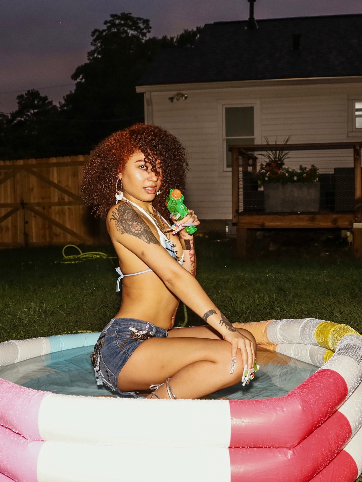 Lailah seated in an inflatable pool in a summer fashion editorial